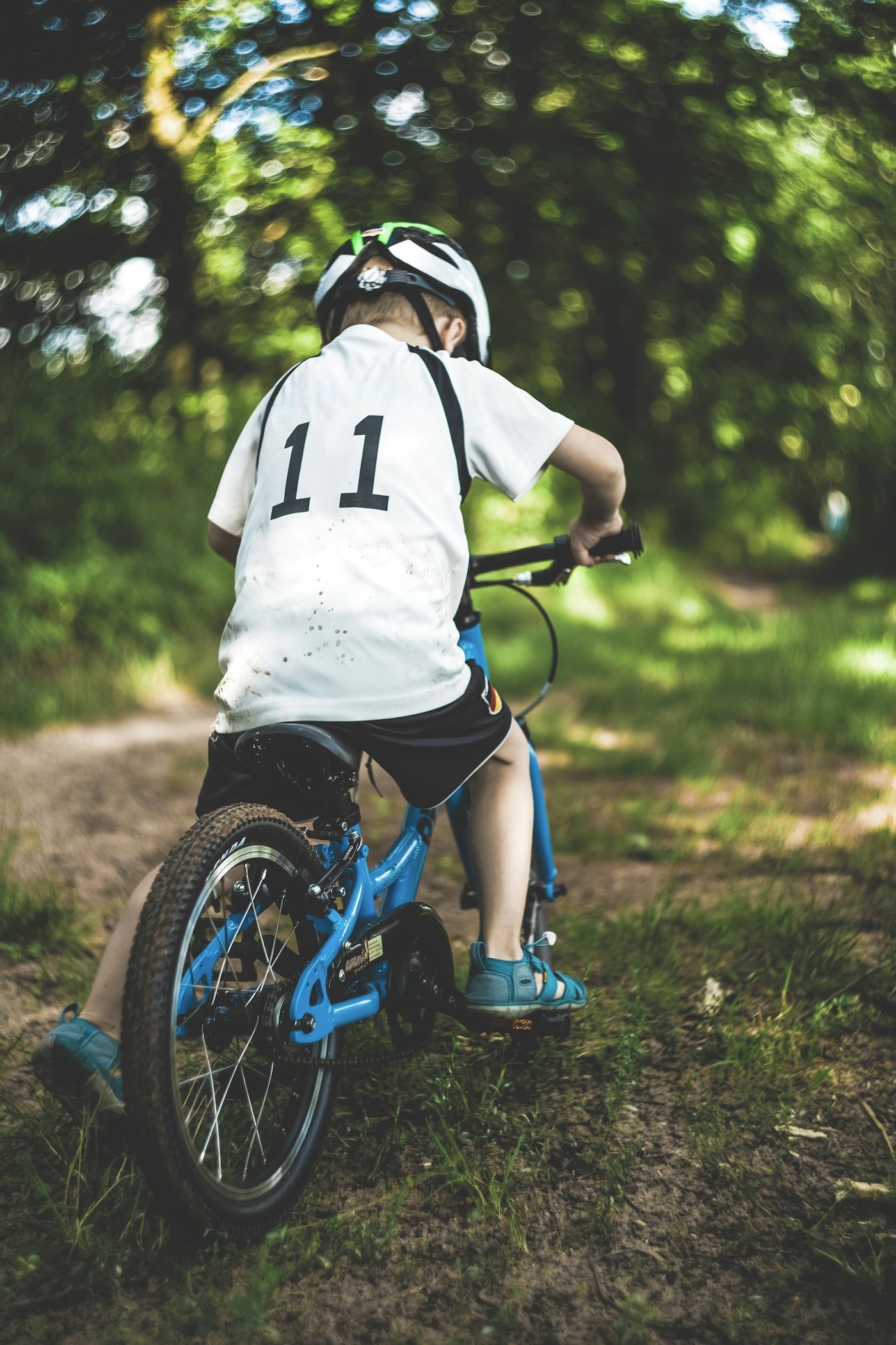 A child riding a kids' bike along a woodland trail